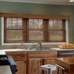 Horizontal wood blinds partially open in the kitchen over the sink,.