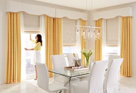 woman adjusting draperies in dining room