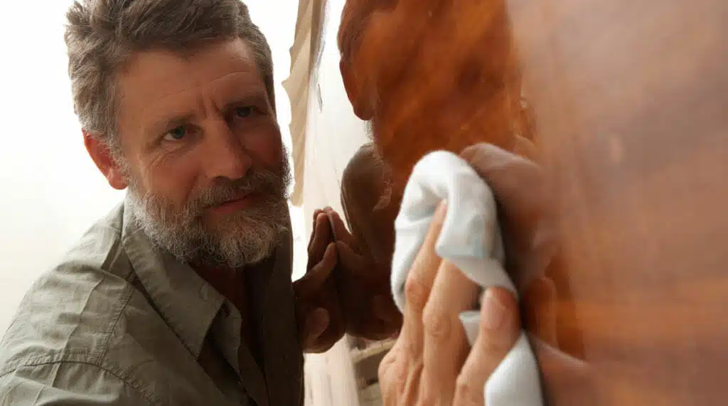 Mature man polishing boat in boat building workshop, close-up
