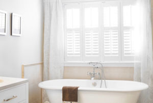 Sheer curtains combined with shutters creates soft elegance in bathroom windows.