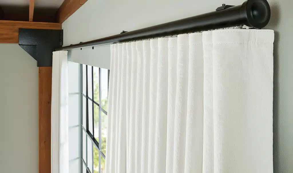 drapery-natural-shades-with-side-panels White blackout drapery panel on decorative black curtain rod in modern industrial-style room with wood beams and large grid windows