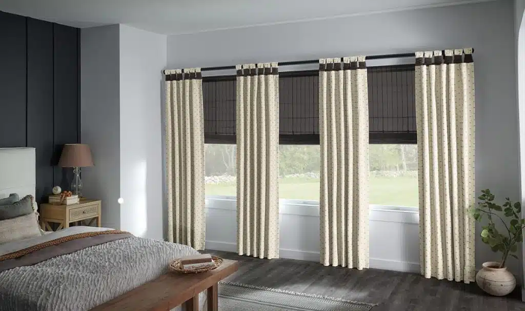 Bedroom with natural woven blackout shades layered behind patterned side panel drapery