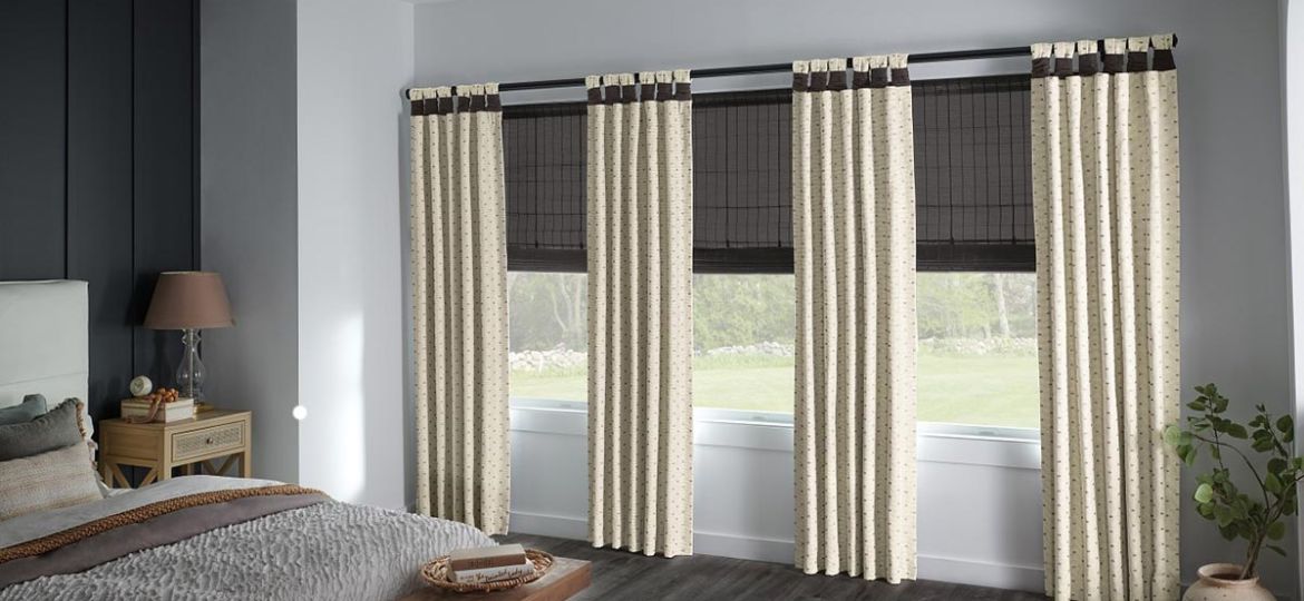 Bedroom with natural woven blackout shades layered behind patterned side panel drapery