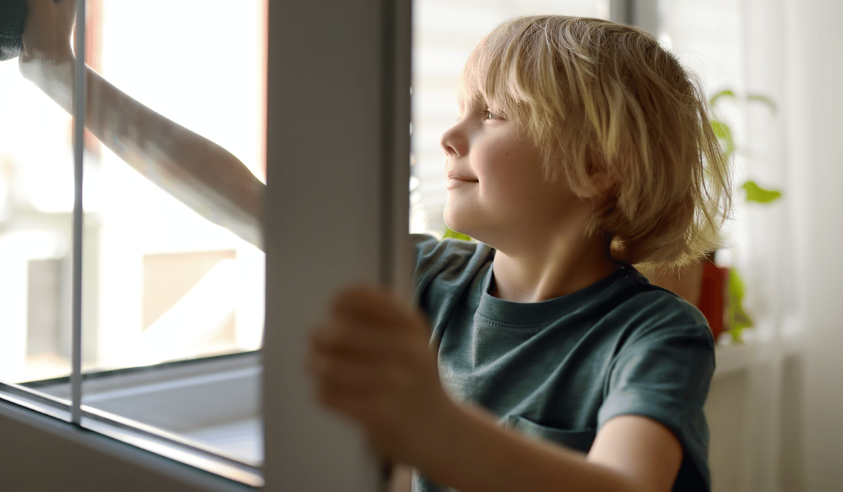 a young child smiles while safely opening blinds with motorized controls