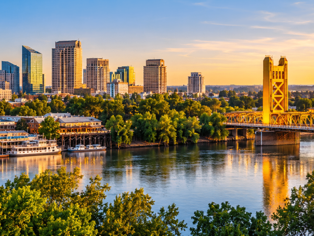 Sacramento skyline at sunset featuring the iconic Tower Bridge, Sacramento River, and downtown waterfront in Sacramento, California.
