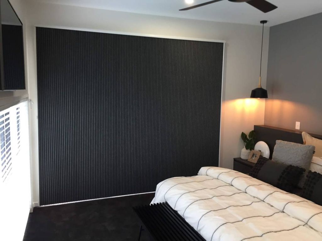 Vertical honeycomb blackout shades covering sliding doors in modern bedroom